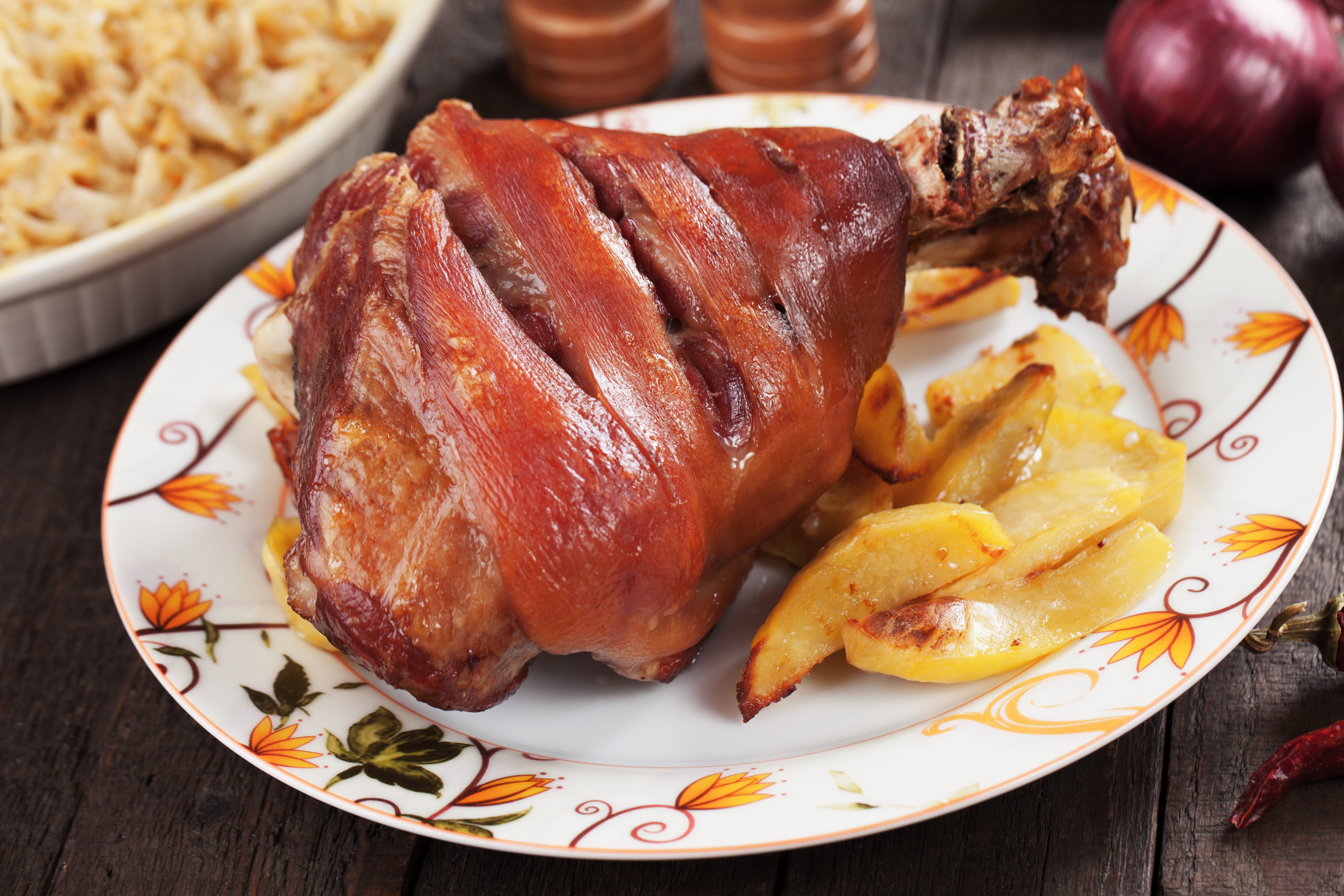 Roasted pork knuckle served with baked potato and sauerkraut